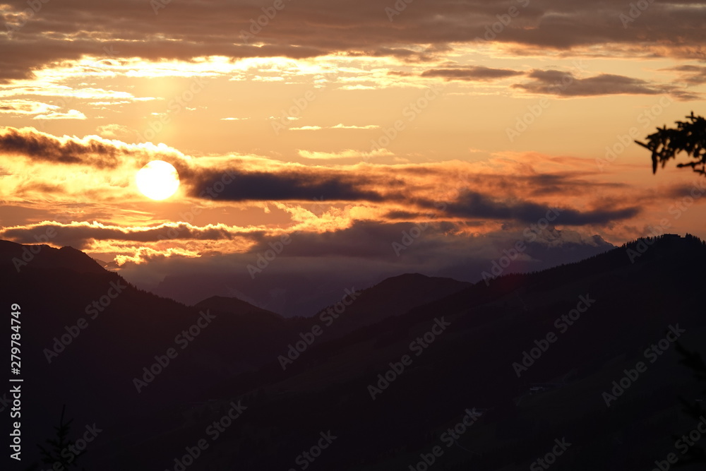 beautiful sunset with orange sky, clouds and tree silhouette in the mountains beautiful sunset with orange sky, clouds and tree silhouette in the mountains