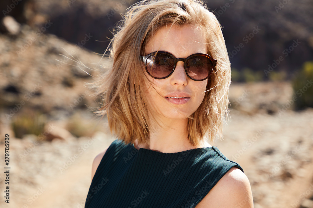 Beautiful model in sunglasses looking at camera in desert Beautiful model in sunglasses looking at camera in desert