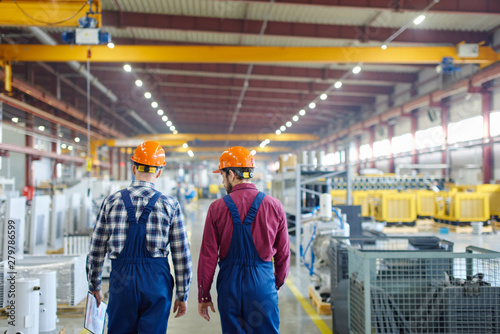 Engineers walking along the plant they work at shot from the back.