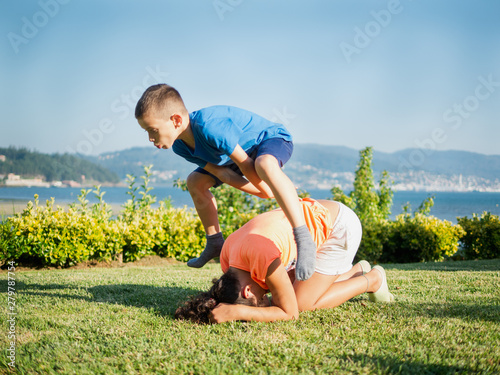 Fotografie children playing leapfrog in the grass