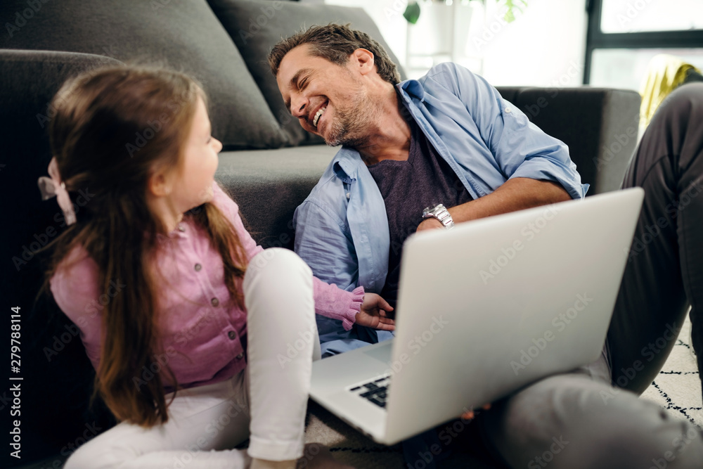 Cheerful father laughing while having fun with his daughter at home. Cheerful father laughing while having fun with his daughter at home.