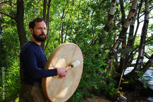 A bearded man plays drums in forest Emotional meditating Lifestyle. Introspection Relaxing photo