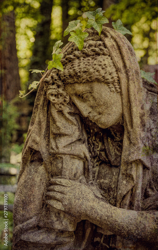 Marble statue and an ancient abandoned Gothic cemetery © konoplizkaya