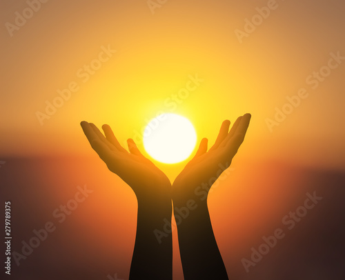 International Day of Peace concept: Raised hands catching sun on sunset sky