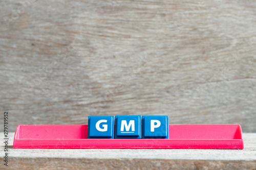 Tile letter on red rack in word GMP (Abbreviation of good manufacturing practice) on wood background photo