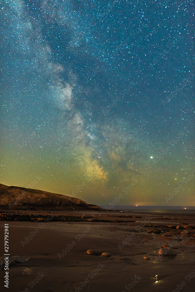Milky Way starscape over beach, rocks and water at night