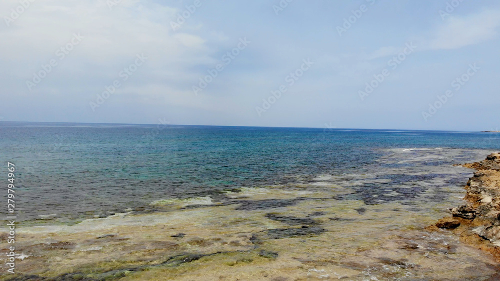 The rocky coast of Cyprus with azure water near Ayia Napa. Flying drone over the sea