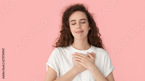 Grateful woman touch heart with hands isolated on pink background