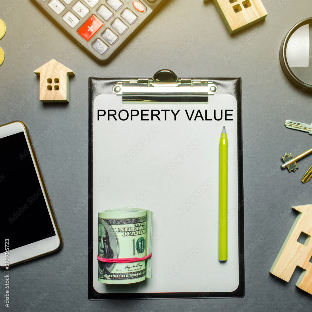 Table with wooden houses, calculator, coins, magnifying glass with the word Property value. The contract for real estate appraisal. Rate the property. Valuation house. Appraisal Services. Flat lay