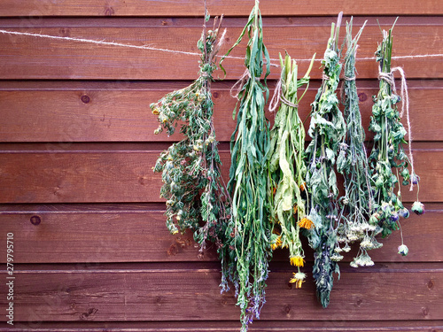 Motherwort, willow herb, Kuril tea, calendula, yarrow and clover flowers are dried on a rope on a wooden background, preparation of medicinal herbs for the winter for the prevention and treatment
