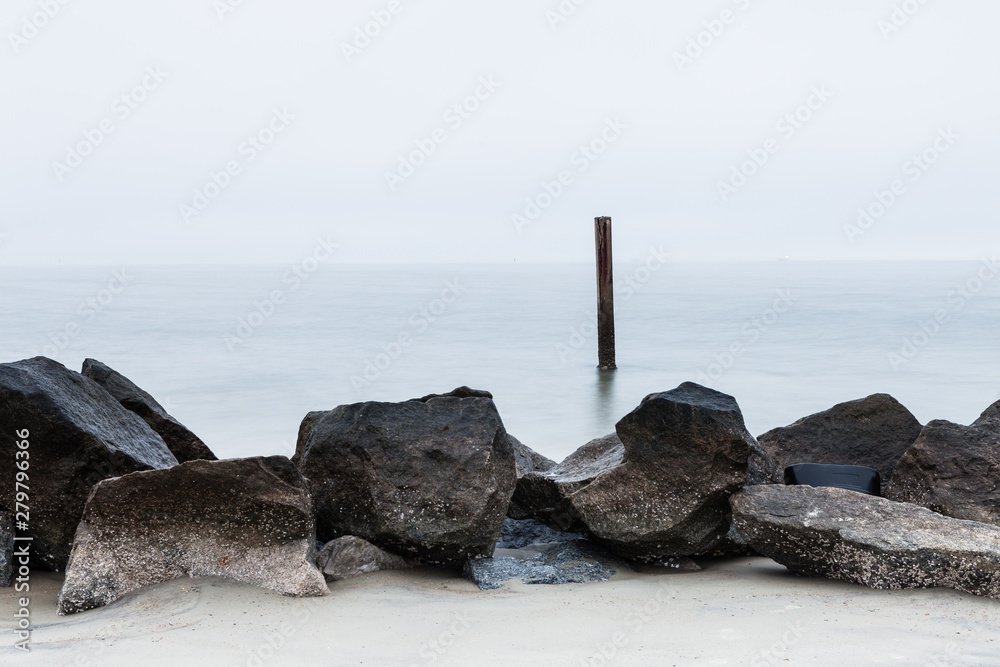 long exposure minimalistic photo of sea and rocks. Stone breakwater