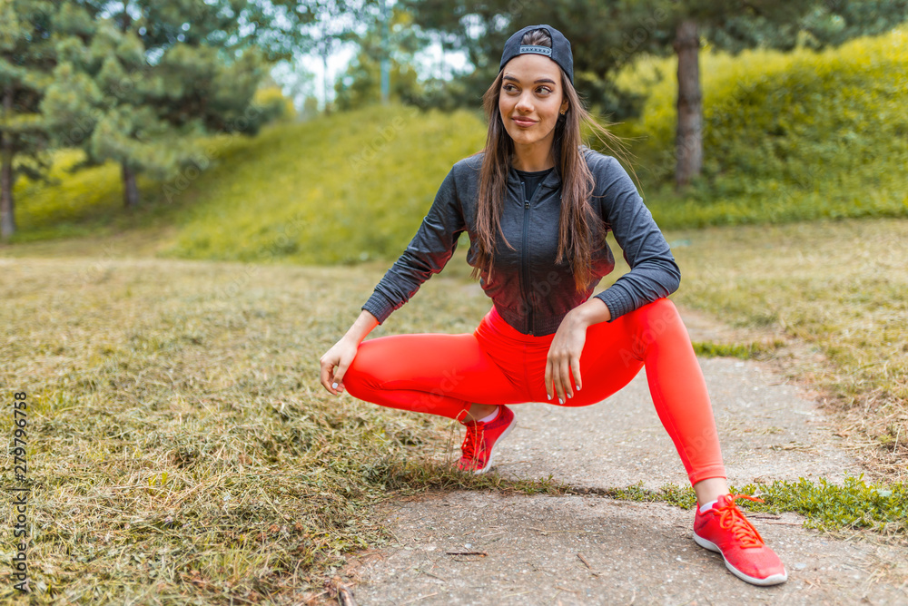 Young woman posing in fitness outfit. Portrait of young sports woman  relaxing outdoors after workout. Female jogger in bright sportswear smiling  looking away, advertising for sports Stock Photo