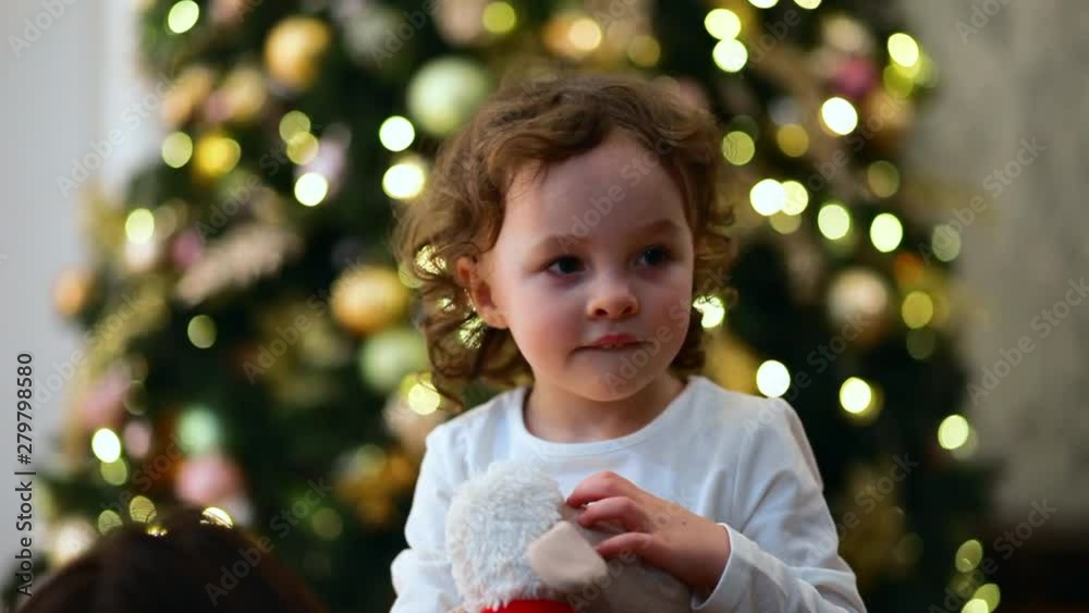 Close-up portrait of a little girl with the Christmas tree as the background. Close-up portrait of a little girl with the Christmas tree as the background.