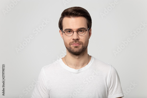 Headshot portrait of serious guy in glasses on grey background
