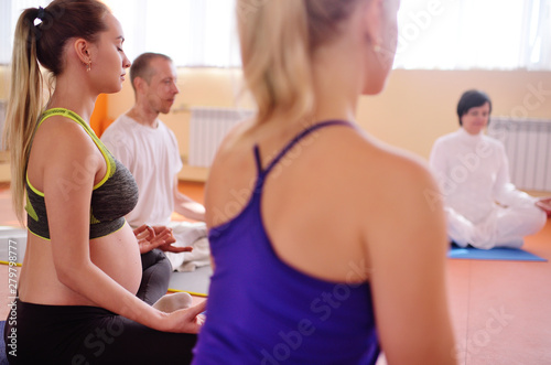 Beautiful pregnant woman performs aerobic exercises or asanas with a group of yoga in the fitness center © Evgeniy Kalinovskiy