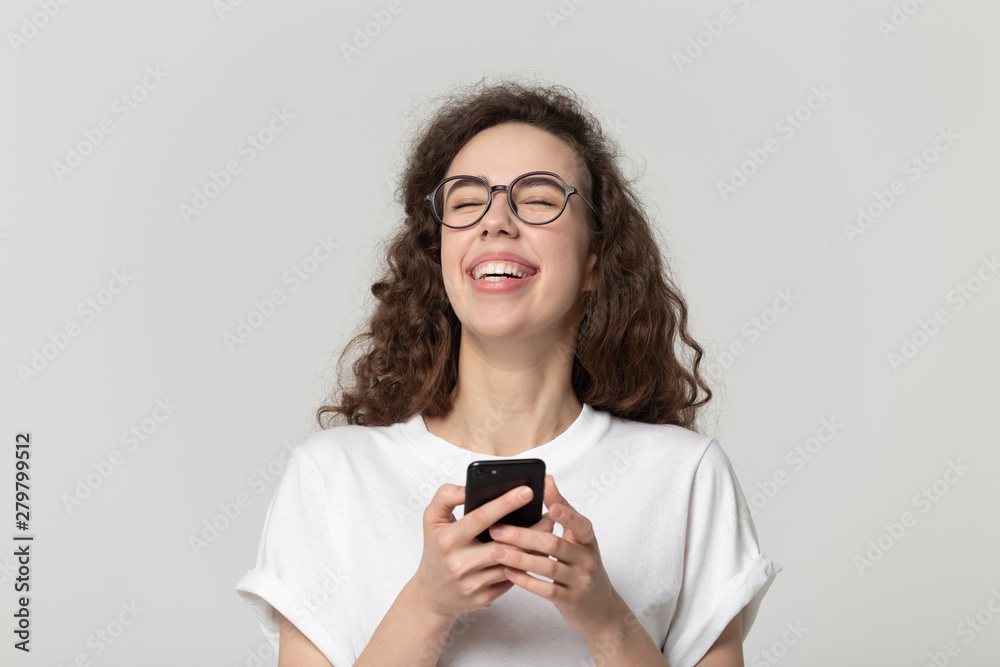 Cheerful woman laughing using smartphone apps studio shot Cheerful woman laughing using smartphone apps studio shot