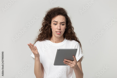 Irritated woman looking at tablet screen feels angry studio shot