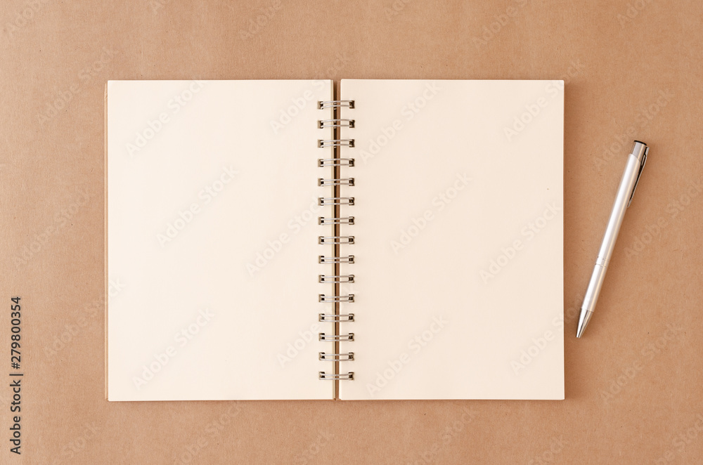An empty notebook that has been left open and pen on an old brown background.