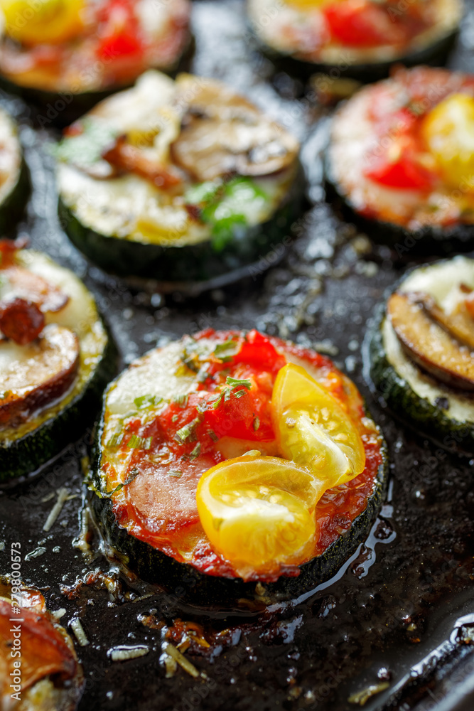Mini pizzas, Zucchini pizza bites from zucchini slices with the addition of brown mushrooms, mushroom chanterelles, mozzarella cheese, salami sausage, cherry tomatoes and herbs on a black background Mini pizzas, Zucchini pizza bites from zucchini slices with the addition of brown mushrooms, mushroom chanterelles, mozzarella cheese, salami sausage, cherry tomatoes and herbs on a black background