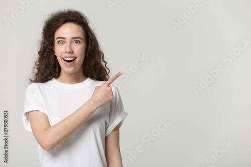 Surprised woman pointing finger at copy space studio shot