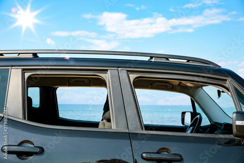 Black summer car on the sunny sandy beach. Blue clear sunshine sky view in distance.  © magdal3na