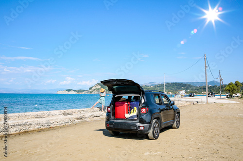 Black summer car and a girl on the beach. Happy smiling woman on the seashore view.