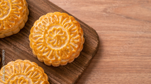 Round shaped moon cake Mooncake - Chinese style pastry during Mid-Autumn Festival / Moon Festival on wooden background and tray, top view, flat lay.