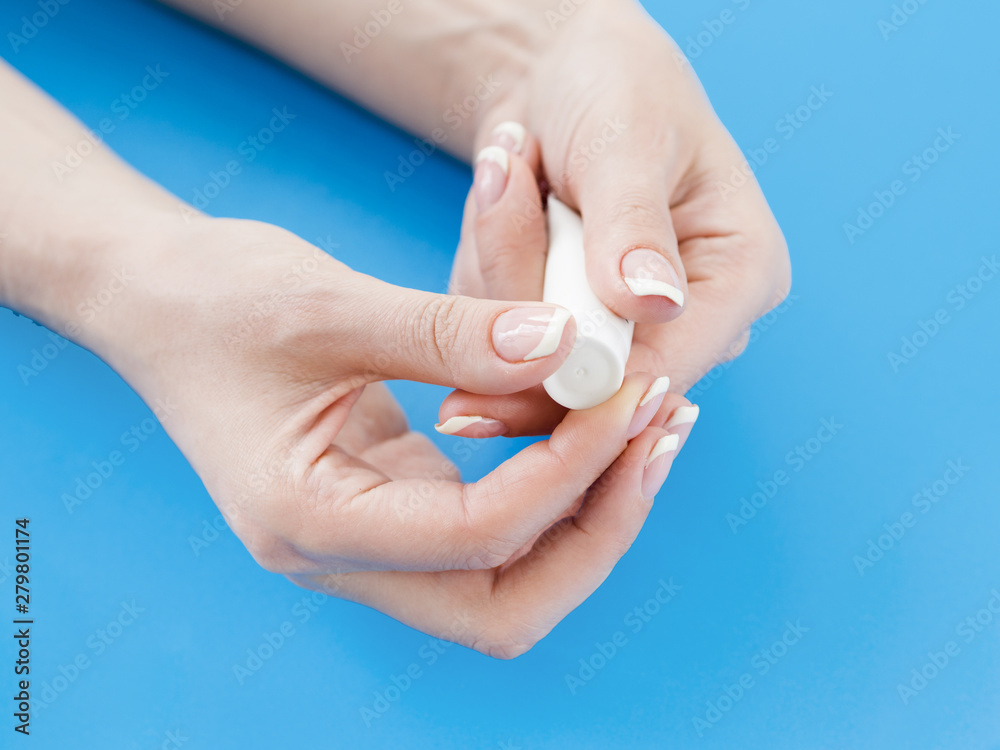 Woman hands holding cream tube on blue background Woman hands holding cream tube on blue background