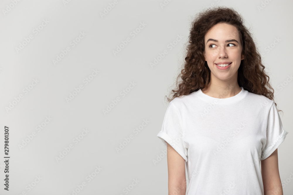 Attractive young woman standing aside looking at copyspace grey background Attractive young woman standing aside looking at copyspace grey background