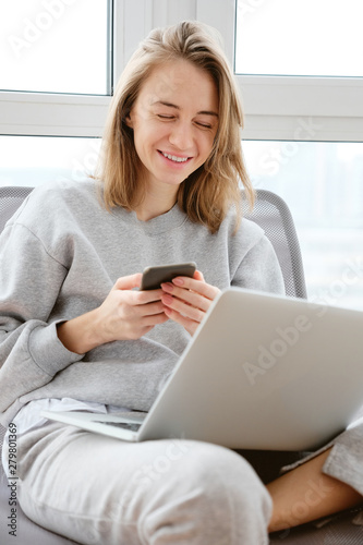 Pretty mid age woman using gadgets while sitting near the window