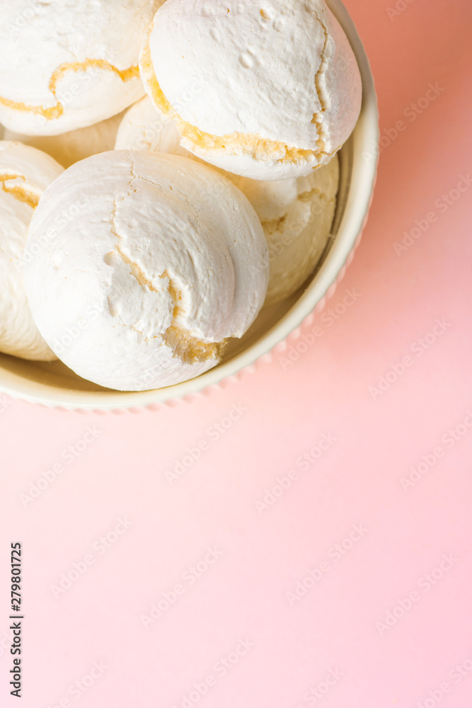 Home baked meringue cookies in white bowl on light pink background. French Italian Swiss cuisine confection coffee dessert recipe poster cafe menu Home baked meringue cookies in white bowl on light pink background. French Italian Swiss cuisine confection coffee dessert recipe poster cafe menu