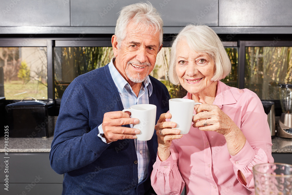 Senioren Paar mit Becher Kaffee in der Küche Senioren Paar mit Becher Kaffee in der Küche