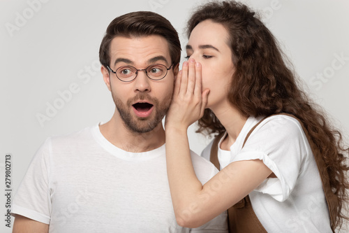 Fotografie Girlfriend whispering in ear to boyfriend a secret studio shot
