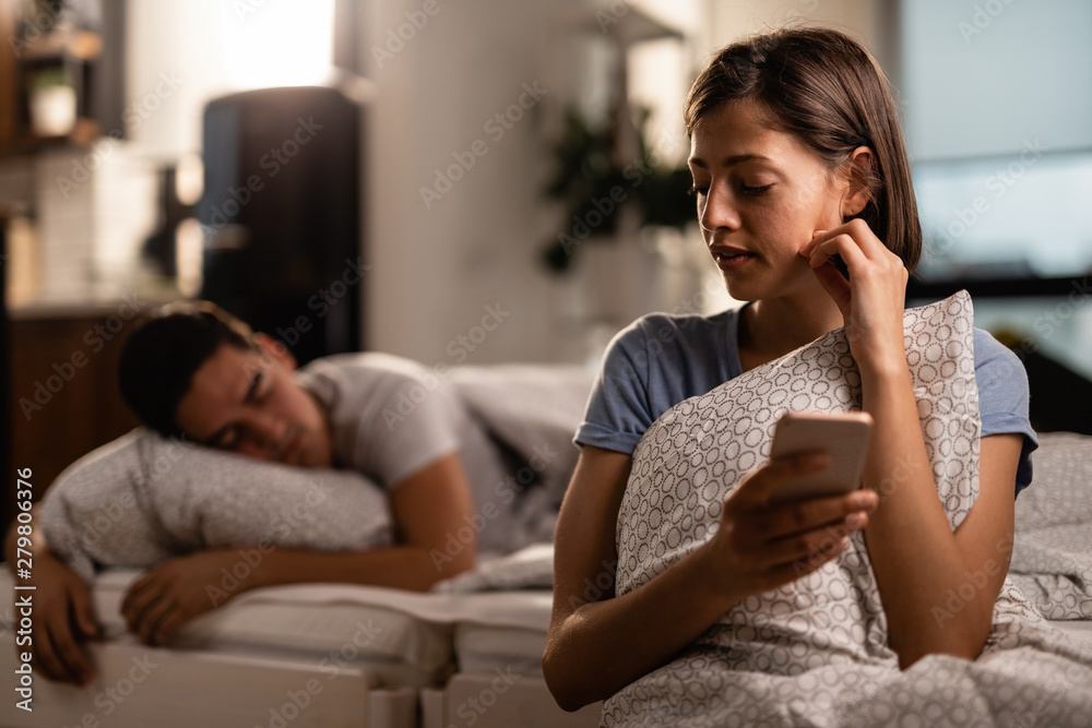Young woman using mobile phone and cheating on her boyfriend.