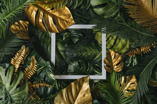 Creative nature background. Gold and green tropical palm leaves. Minimal summer abstract jungle or forest pattern. White paper frame copy space.
