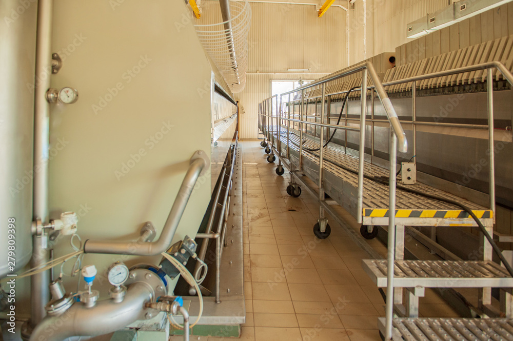 Equipment for preparation of beeer..Lines of metal tanks in modern brewery. Manufacturable process of brewage. Mode of beer production. Inside view of modern brewhouse with stainless barrels
