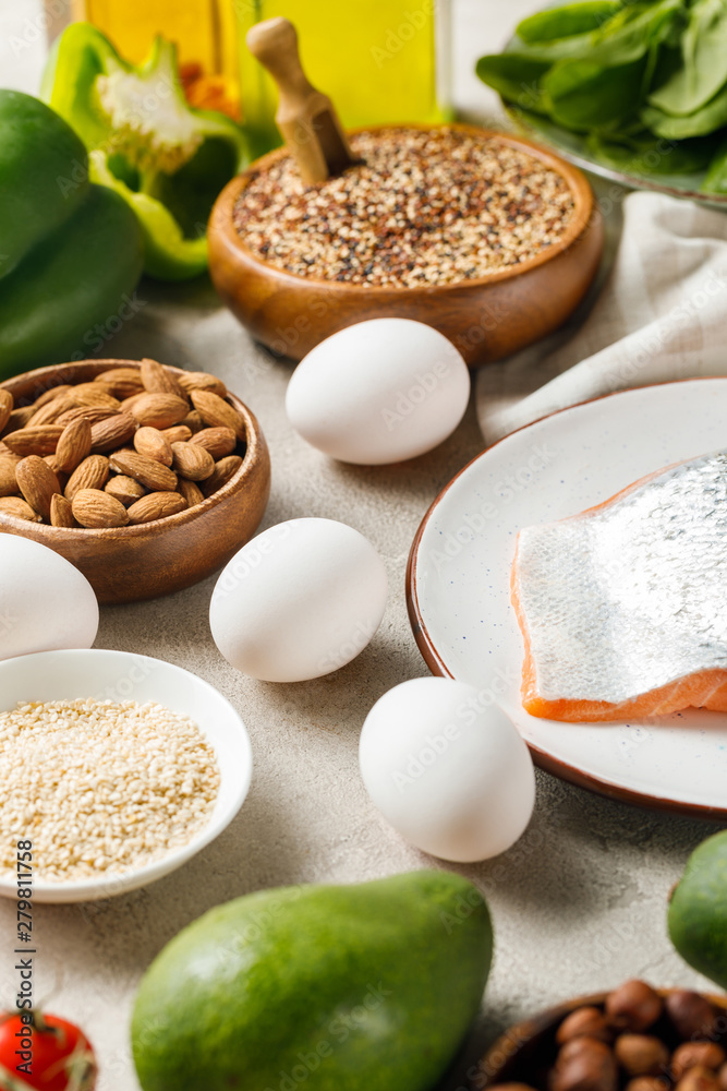 fresh raw salmon on white plate near nuts, vegetables and eggs, ketogenic diet menu fresh raw salmon on white plate near nuts, vegetables and eggs, ketogenic diet menu