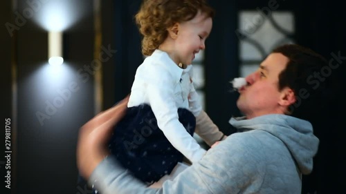 The father puts fake moustache and lifts his little daughter up