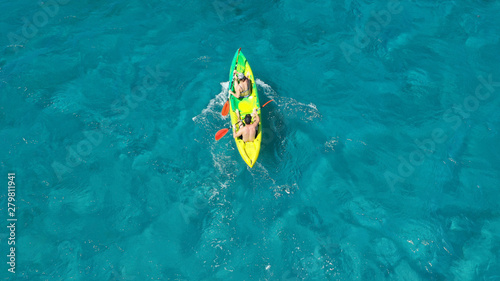 Aerial drone photo of fit couple practising on a colourful canoe in turquoise open ocean bay with crystal clear sea