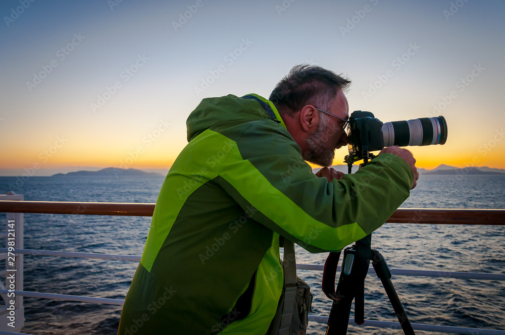 Obraz premium Man taking photographs from the deck of a ship at sunset