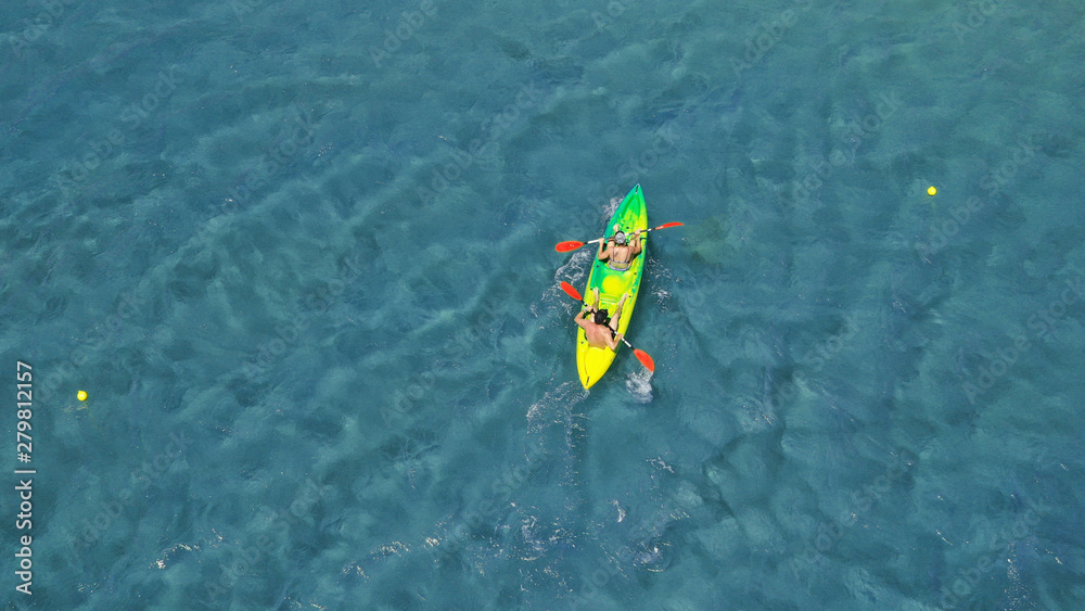 Aerial drone photo of fit couple practising on a colourful canoe in turquoise open ocean bay with crystal clear sea Aerial drone photo of fit couple practising on a colourful canoe in turquoise open ocean bay with crystal clear sea