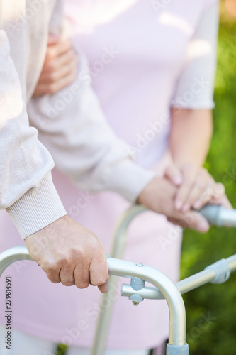 Close up of caring wife holding hand of husband using walker, copy space