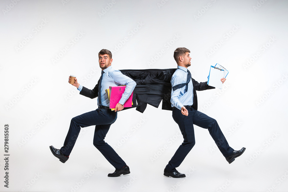 Young man torning between cases and trying to do everything - holding folders and documents on the run in different directions. Concept of office worker's troubles, business, problems, stress. Young man torning between cases and trying to do everything - holding folders and documents on the run in different directions. Concept of office worker's troubles, business, problems, stress.