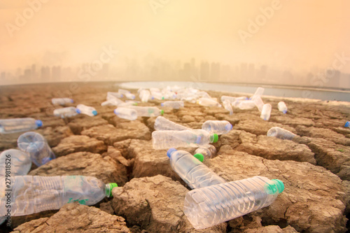 Plastic bottle dirty on dry river with bad environment of air polluted city on background metaphor Environmental damage of Plastic pollution, Polluted environment of toxic waste from urban.