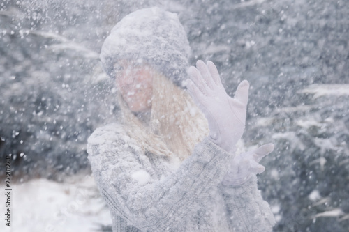 Young beautiful girl with long white hair plays snowballs. She has fun, throws snow and rejoices the snowfall. Winter walk outside.