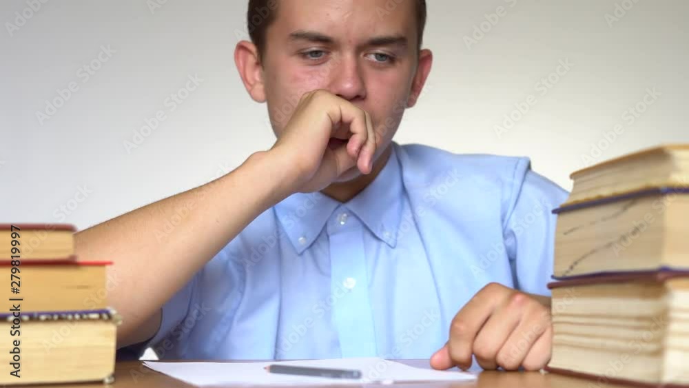 tired sleepy schoolboy tired of studying hard with books in exam preparation, overwhelmed by a school boy, tired of hard work or too much homework tired sleepy schoolboy tired of studying hard with books in exam preparation, overwhelmed by a school boy, tired of hard work or too much homework