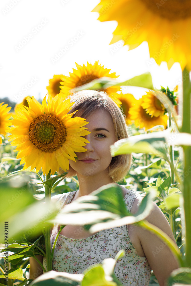 Portrait of a beautiful girl in white dress, with sunflower in a sunflower field on a sunny day Portrait of a beautiful girl in white dress, with sunflower in a sunflower field on a sunny day