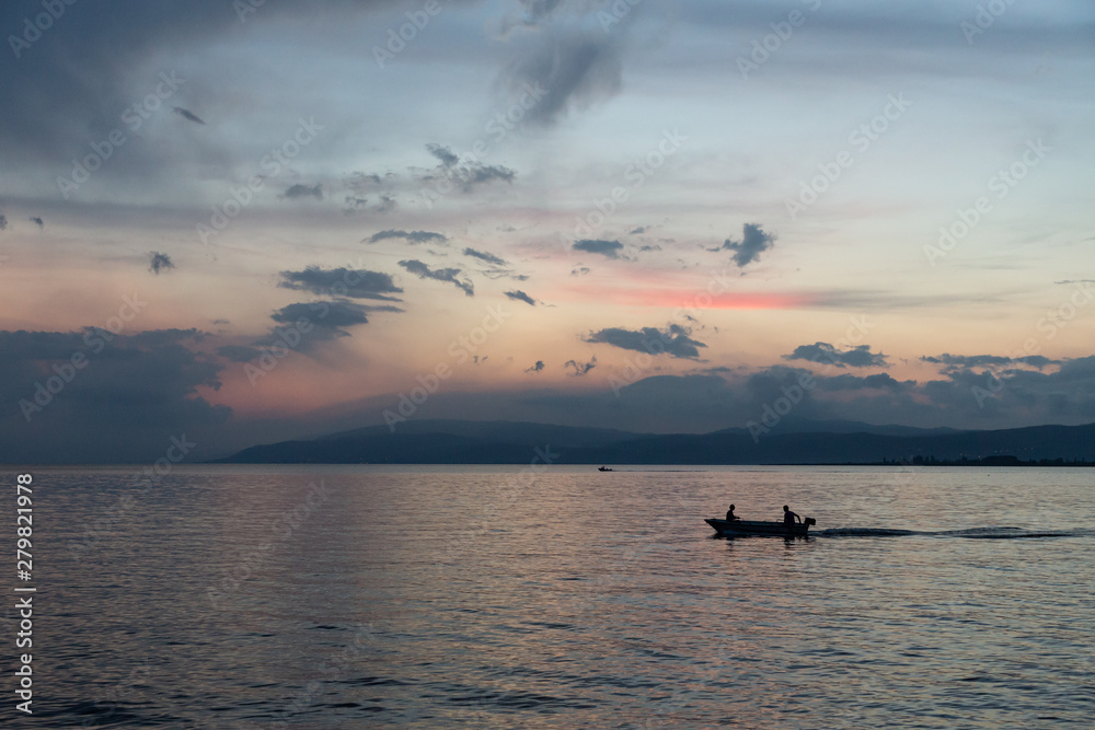 silhouetted boat on the calm waters of Lake Iznik at sunset