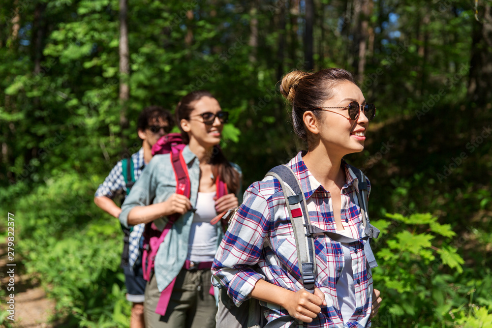 Fototapeta premium travel, tourism, hike and people concept - group of friends walking with backpacks in forest