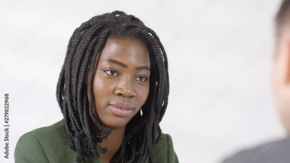 Medium shot of cheerful black woman smiling and talking to HR manager during job interview Medium shot of cheerful black woman smiling and talking to HR manager during job interview